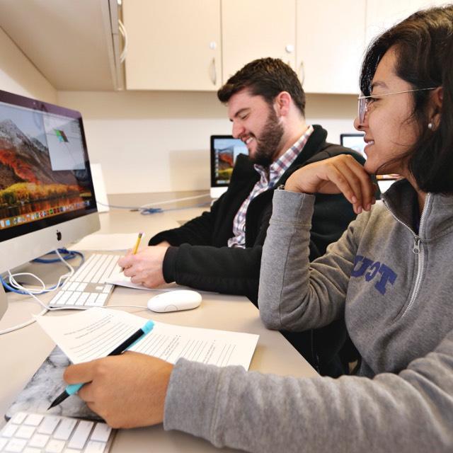 Students discuss details of a curriculum plan while working at computer workstations