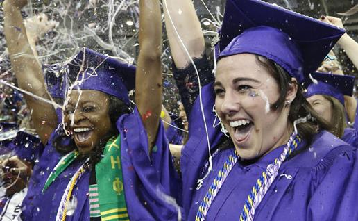 TCU graduates in caps and gowns set off handheld confetti cannons spewing multi-colored confetti into the air